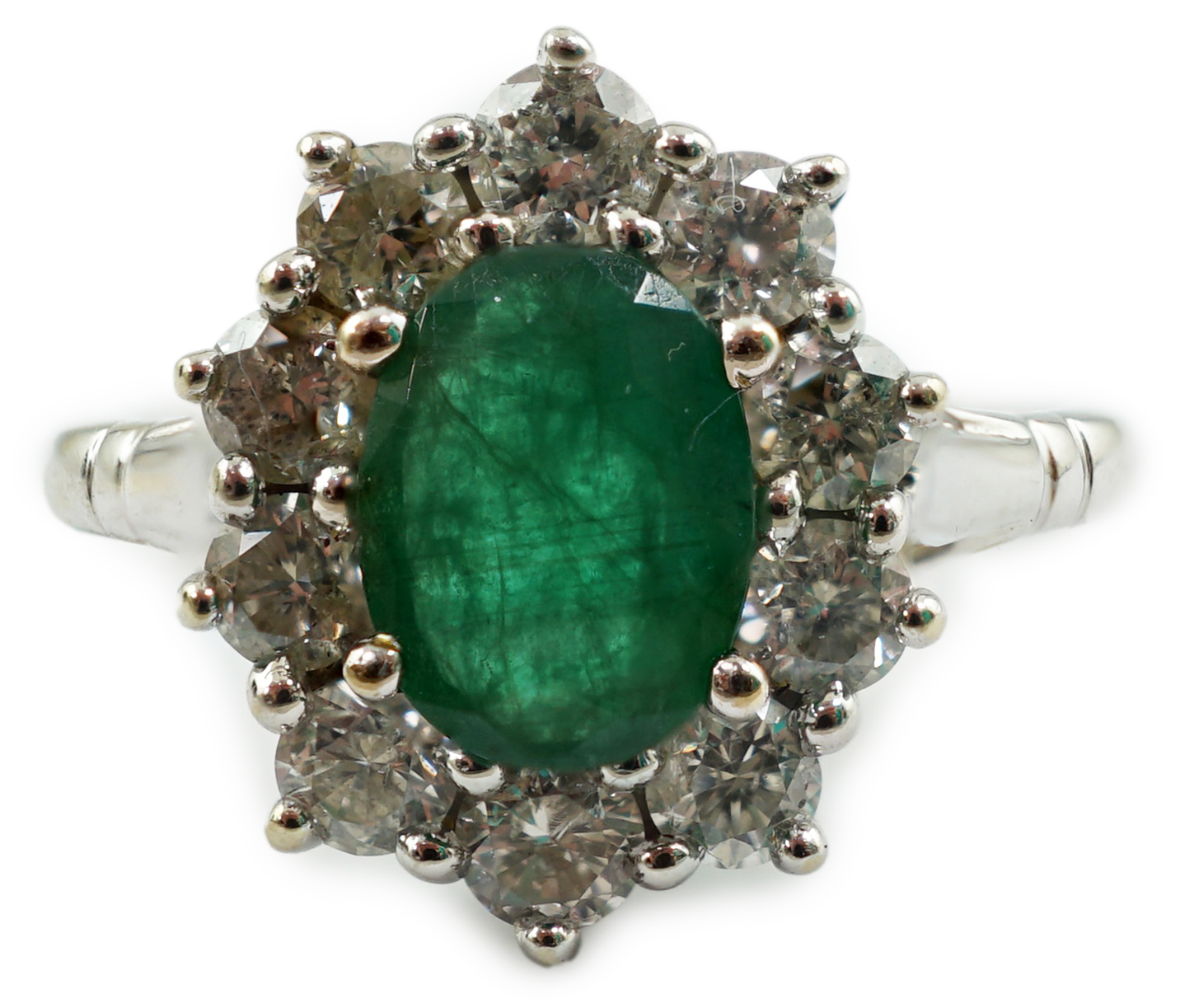 A modern 18ct white gold, single stone oval cut emerald and ten stone diamond set oval cluster ring